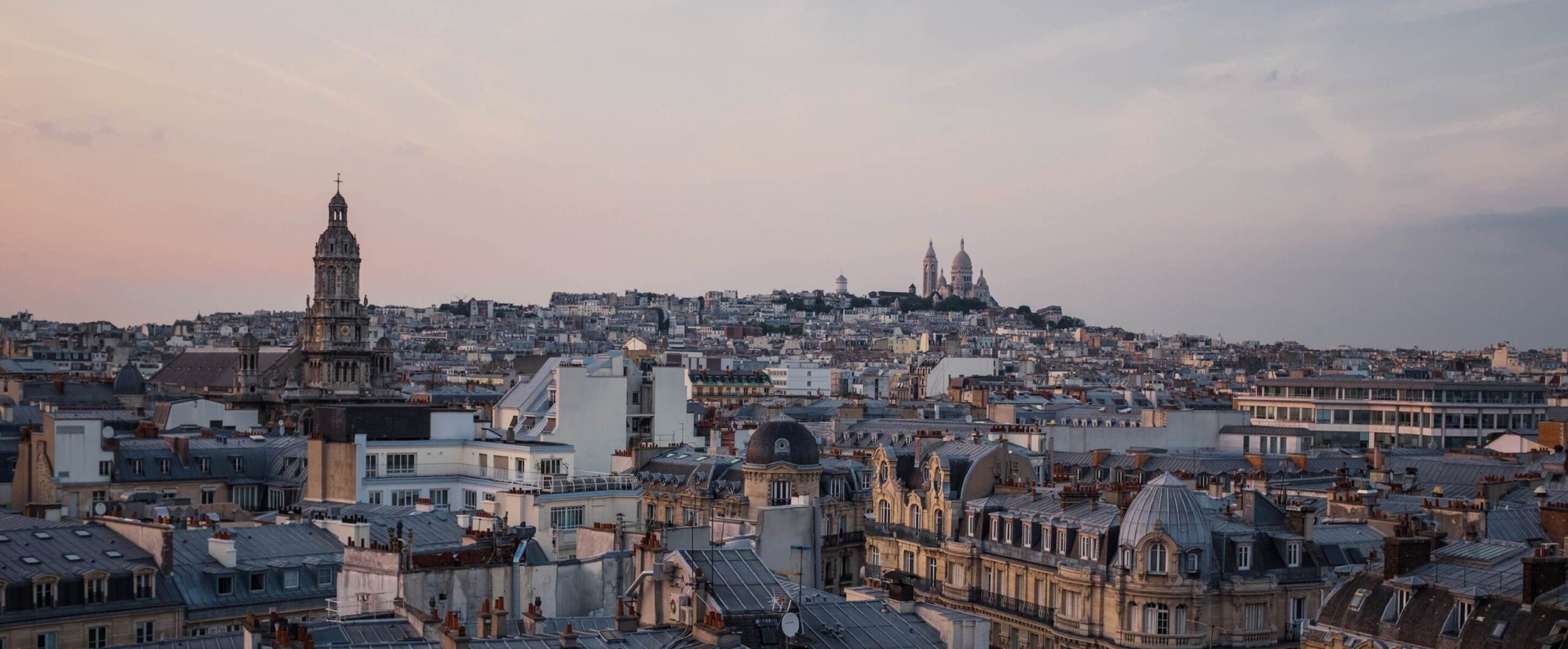 Paris skyline at dusk with iconic Sacré-Cœur Basilica.